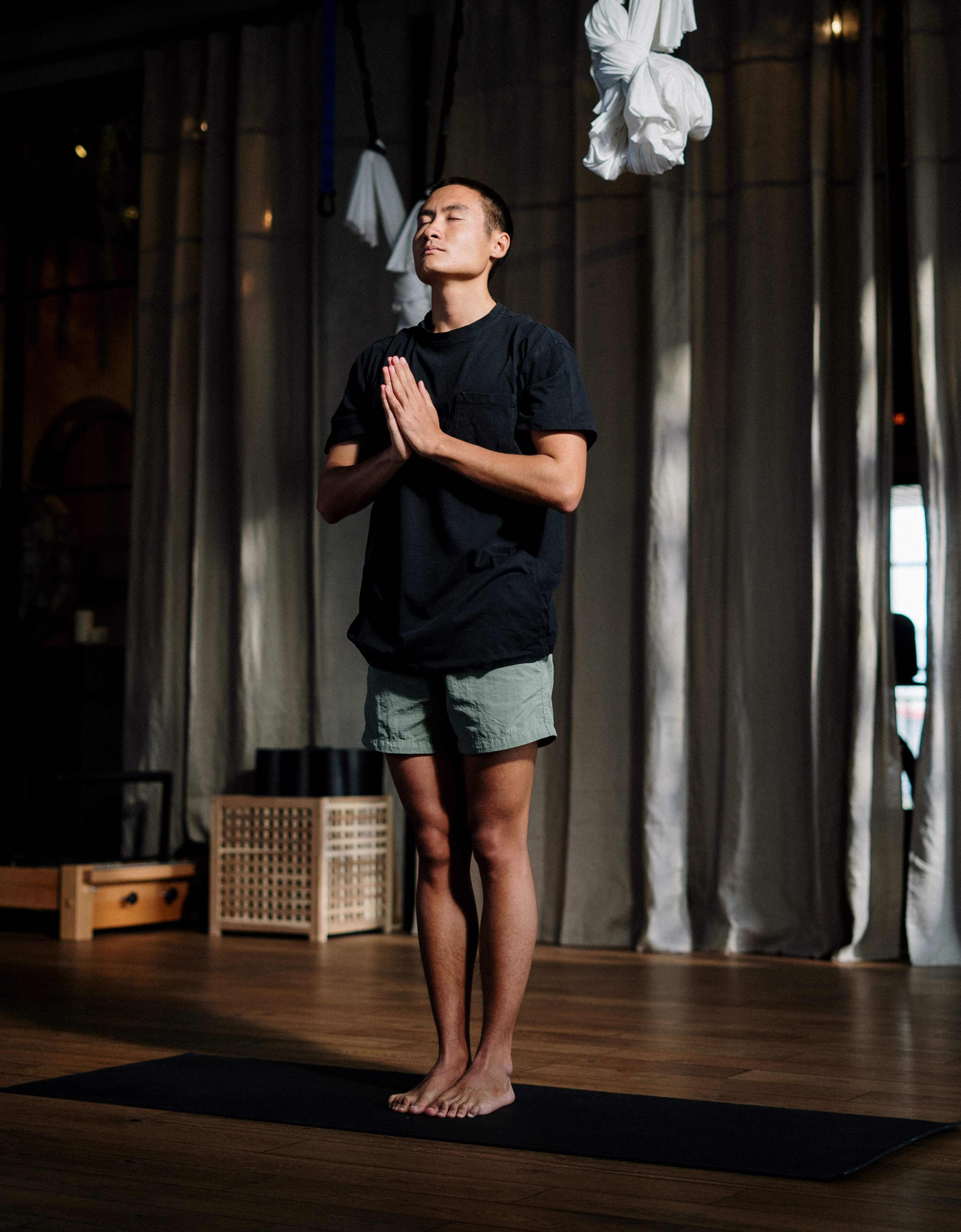 man standing with hands in prayer position in a peaceful meditative pose